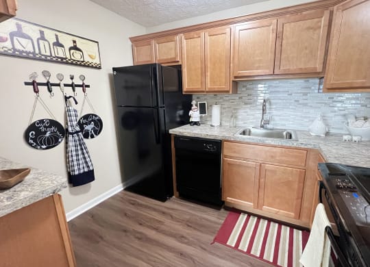 a kitchen with black appliances and wooden cabinets at Fox Run Apartments, Cincinnati