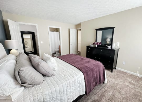 a bedroom with a bed and a dresser and a mirror at Fox Run Apartments, Cincinnati