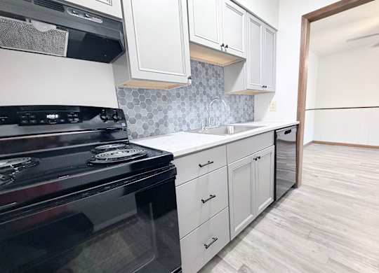 A kitchen with a black stove top oven and white cabinets.