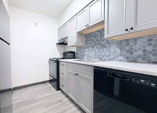 A kitchen with black appliances and white cabinets.