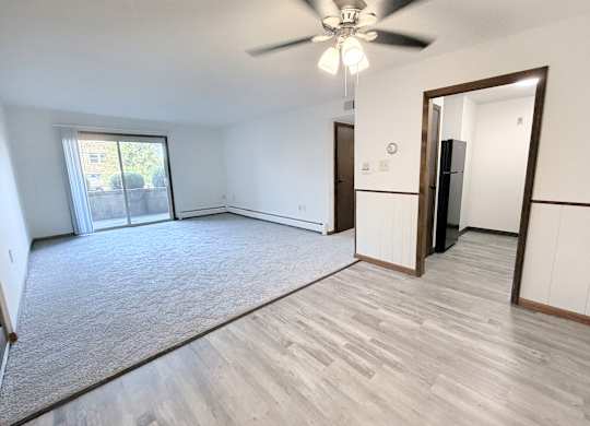 A room with a ceiling fan and a door leading to another room.