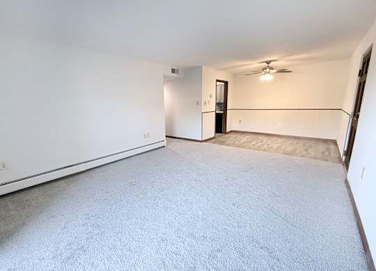 A spacious room with a carpeted floor and a ceiling fan.