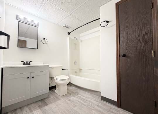 A white toilet sits in a bathroom next to a bathtub.