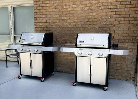 Two gas grills are on a patio.