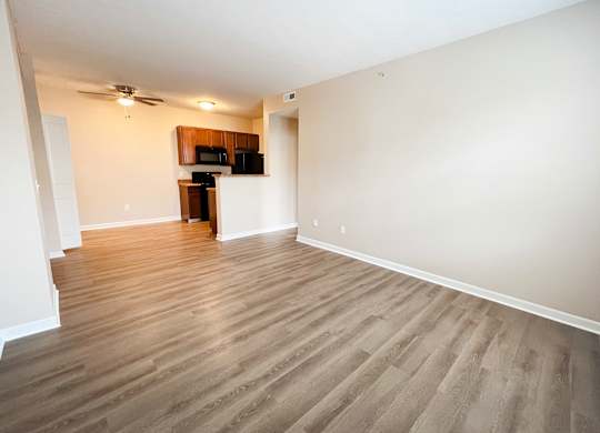 an empty living room with wood flooring and a kitchen at The Residences at Liberty Crossing, Columbus, OH, 43235