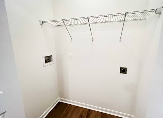 a room with a white wall and a closet with a rack on the wall at The Residences at Liberty Crossing, Columbus, 43235
