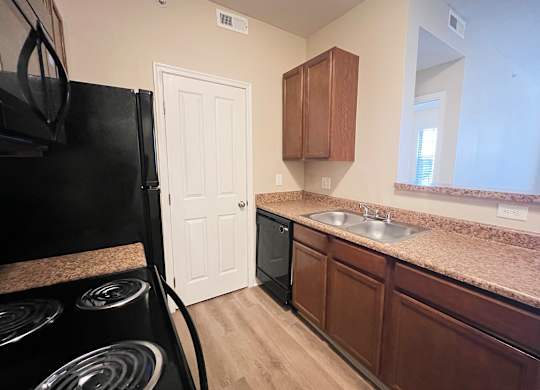 full kitchen with black appliances and granite counter tops in an apartment