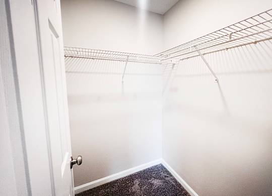 A white door is open to a hallway with a metal rack on the wall.