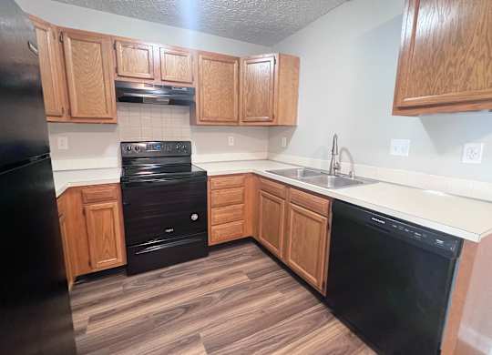 A kitchen with black appliances and wooden cabinets.