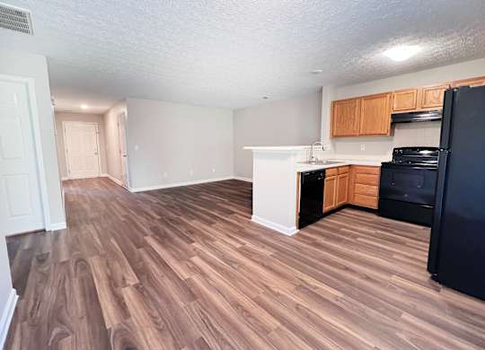 A kitchen with black appliances and wooden floors.