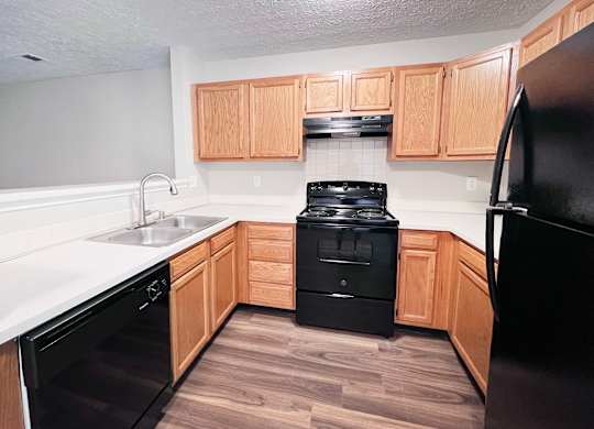 A kitchen with black appliances and wooden cabinets.