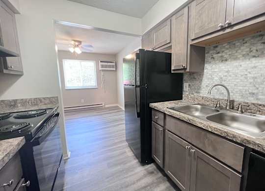 A kitchen with a black fridge and a marble countertop.