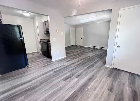 A kitchen area with a black fridge and a grey floor.