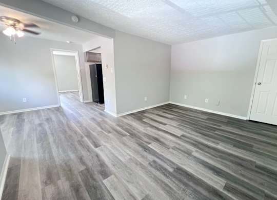 A room with a ceiling fan and wood flooring.