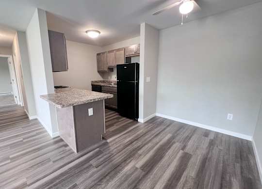 A kitchen area with a black fridge and a countertop.