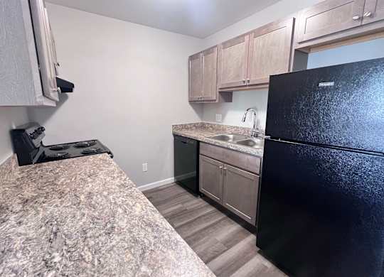 A kitchen with a black refrigerator and granite countertop.