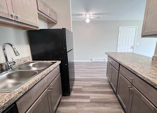 A kitchen with a black refrigerator and granite countertops.