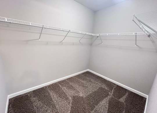 A walk-in closet with a carpeted floor and metal shelving.