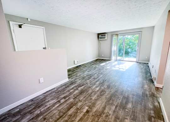 A room with wood flooring and a sliding glass door leading outside.