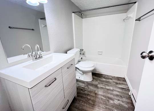 A white bathroom with a toilet, sink, and mirror.