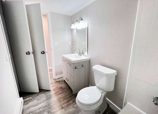A white toilet in a bathroom with a white cabinet and a white sink.