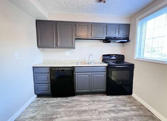 A kitchen with black appliances and grey cabinets.