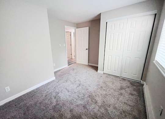 A room with a carpeted floor and two doors.