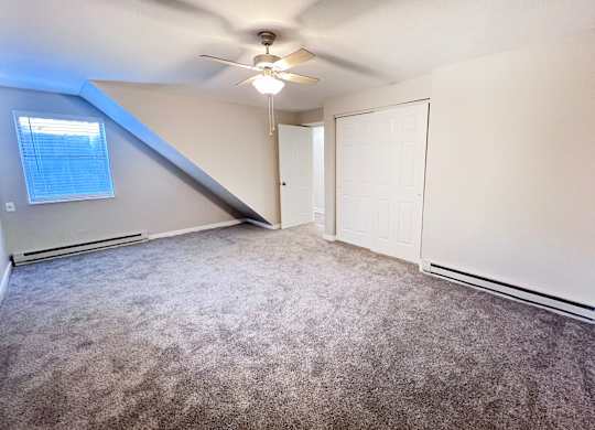 A room with a ceiling fan and carpeted floor.