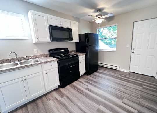 A kitchen with black appliances and white cabinets.