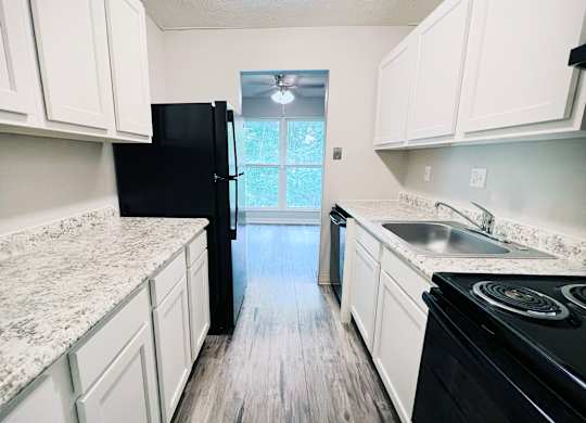 A kitchen with black appliances and white cabinets.