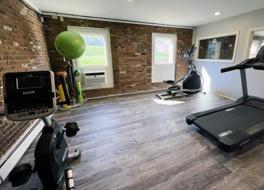 a gym with a brick wall and a treadmill and exercise equipment at Crown Pointe Apartments, Kentucky