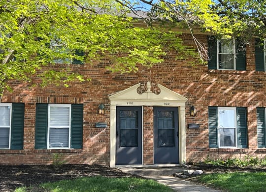 a brick building with blue doors and green shutters at Revere Village Apartments, Centerville, 45458