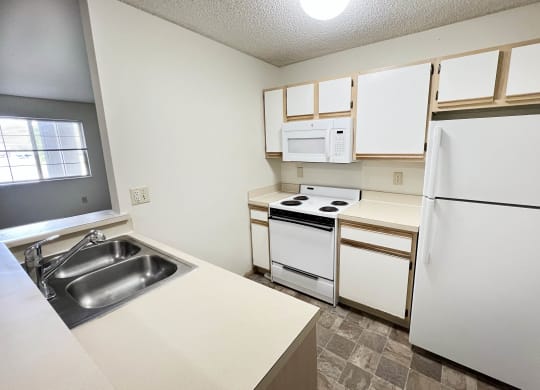 an empty kitchen with white appliances and white cabinets at Eagle Crest Apartments, Galloway, OH 43119
