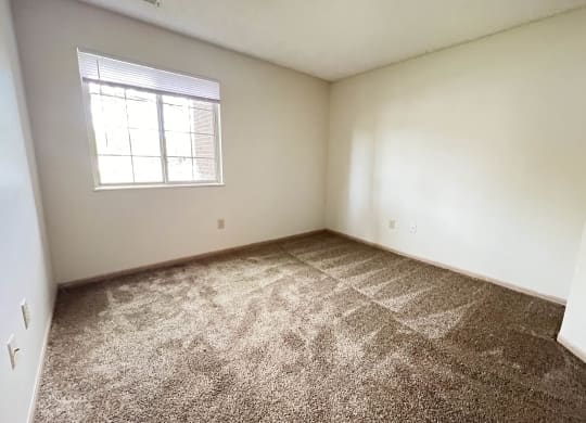 an empty bedroom with carpet and a window at Eagle Crest Apartments, Ohio, 43119