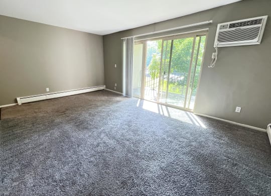 an empty living room with grey carpet and a sliding glass door at Crown Pointe Apartments, Kentucky, 41014