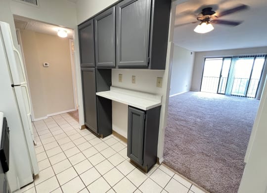 a kitchen with black cabinets and an empty living room with a ceiling fan at Indian Lookout Apartments, Cincinnati, 45238