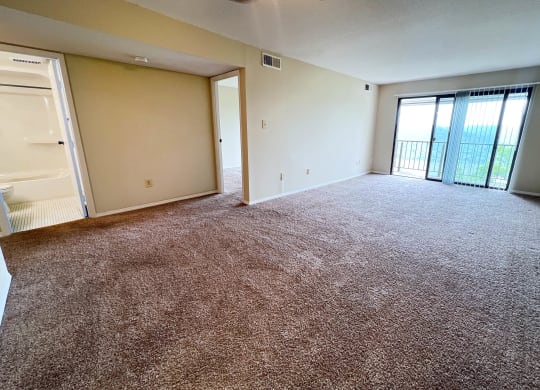 an empty living room with a door to a balcony at Indian Lookout Apartments, Cincinnati