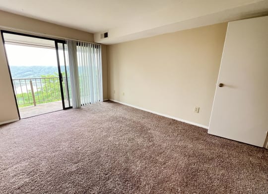 an empty living room with a sliding glass door to a balcony at Indian Lookout Apartments, Cincinnati, Ohio