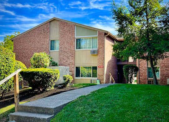 A red brick building with a green lawn in front.