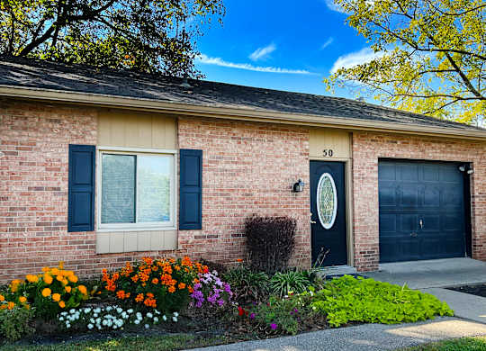 A house with a black door and a window with black shutters.