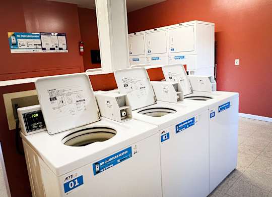 A row of white washing machines are lined up in a room.