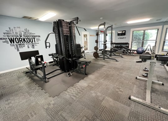 a gym with weights and other equipment in a building with windows at Deercross Apartments, Cincinnati, 45236