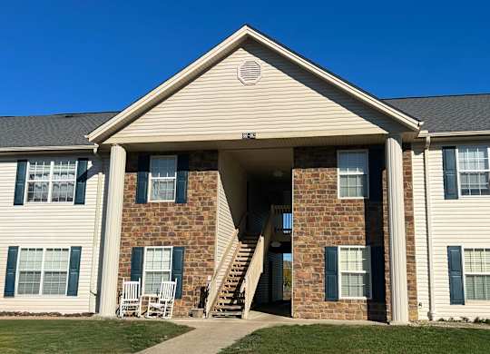 A house with a covered porch and a stone wall.