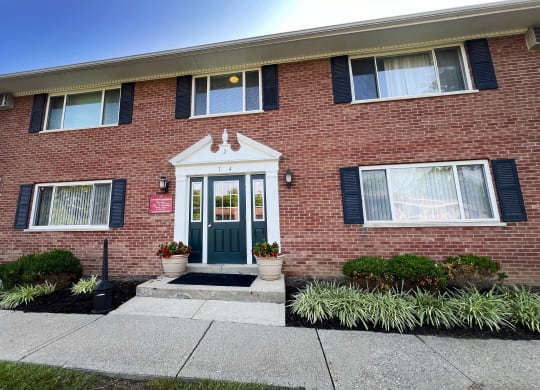 the front of a brick house with a blue door at Sharondale Woods Apartments, Cincinnati