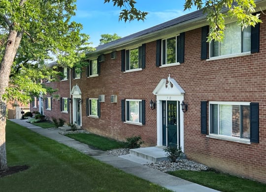 a red brick building with a green lawn and a sidewalk at Sharondale Woods Apartments, Cincinnati, OH