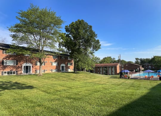 a large yard in front of a brick house with a pool at Sharondale Woods Apartments, Cincinnati