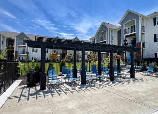 a patio with chairs and a pergola in front of an apartment building at Parkway Trails, Florence, Kentucky