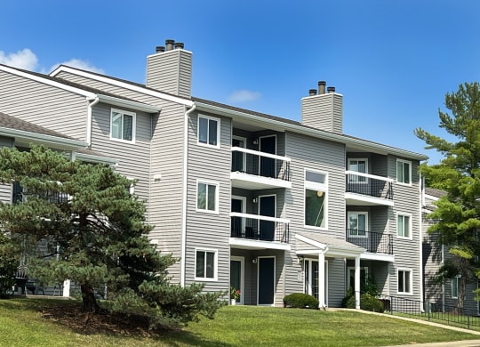an apartment building with gray siding and a tree in the yard at Deercross Apartments, Cincinnati, 45236