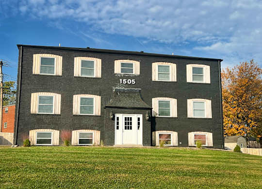 a black brick building with a white door and a lawn