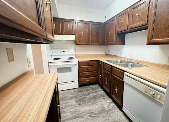 an empty kitchen with white appliances and wooden cabinets at Indian Lookout Apartments, Ohio
